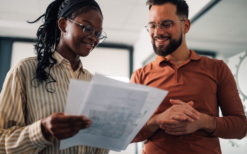Smiling colleagues discussing documents in modern office